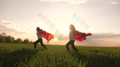 快乐的女孩扮演超级<strong>英雄</strong>，她们穿着红色斗篷在绿地上奔跑，风中飘扬着斗篷。孩子们的游戏和梦想。慢动作青少年梦想成为超级<strong>英雄</strong>。穿着红斗篷的少女